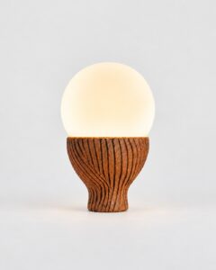 Solbulb table lamp with an opal glass globe on a ridged ceramic base by Hilykan