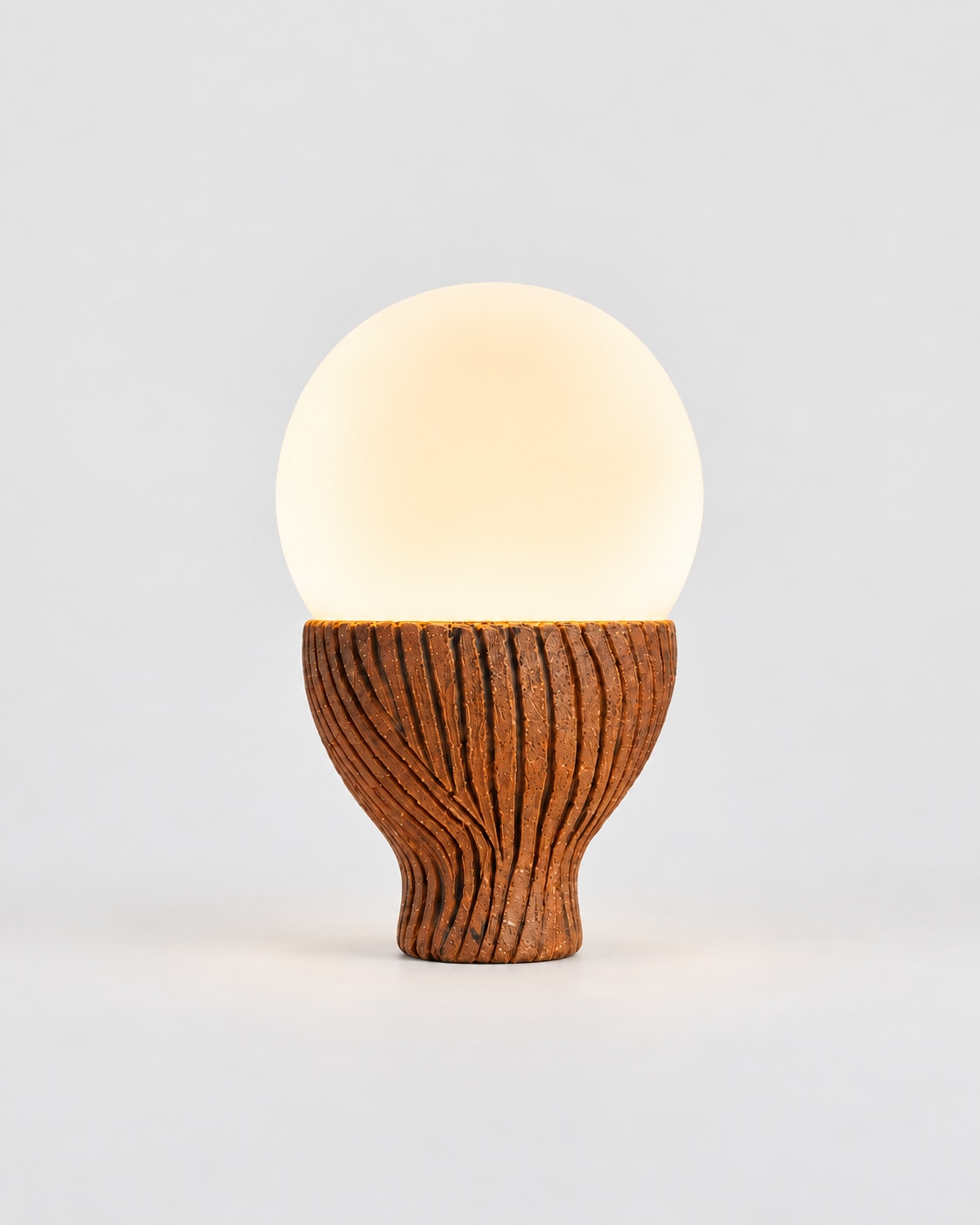 Solbulb table lamp with an opal glass globe on a ridged ceramic base by Hilykan